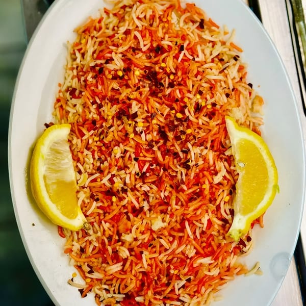 African Paradise Restaurant's colorful rice dish, garnished with two lemon wedges and chili flakes.
